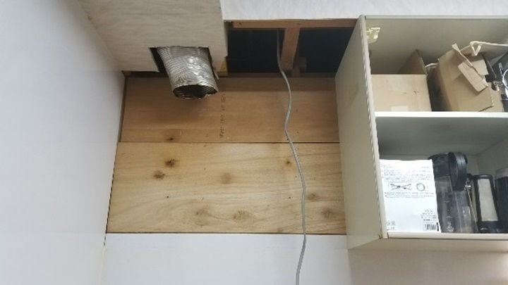 施工中　パネル等についた油汚れをきれいに掃除してから換気扇を取り付けます。