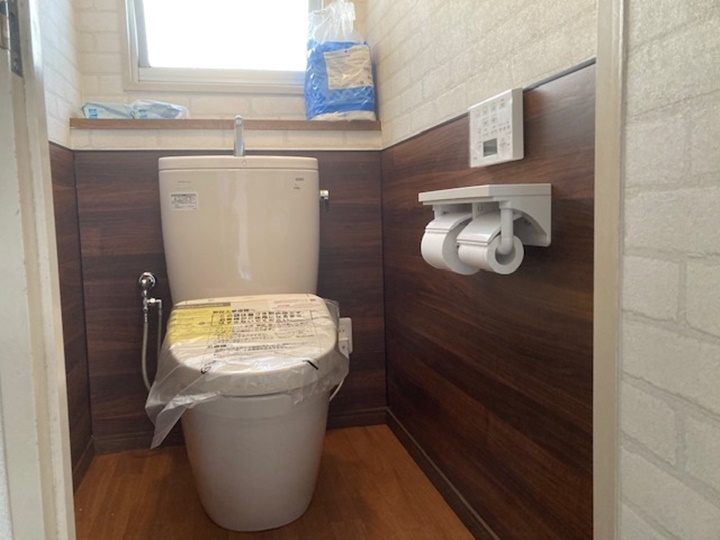 トイレ施工後<br />
トイレ腰下90㎝にパネルを貼り、その他は壁紙、床はクッションフロアで仕上げました。トイレ本体はまだ使用できましたので故障しているウォシュレットのみ交換しました。